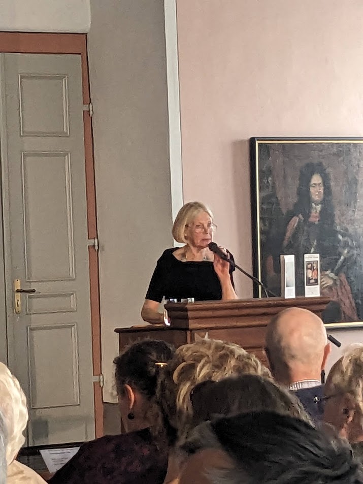 Die Künstlerin Carola Helbing-Erben spricht an einem Mikrofon zum Publikum.